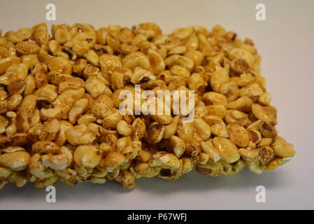 Su un foglio di carta bianca di sfondo è posizionato e posto da una deliziosa e dolce la grigliatura di aria di chicchi di mais, popcorn con caramello Foto Stock