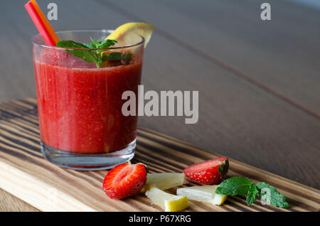 Frullato di fragole con limone, menta e cannucce sul tavolo di legno sfondo Foto Stock