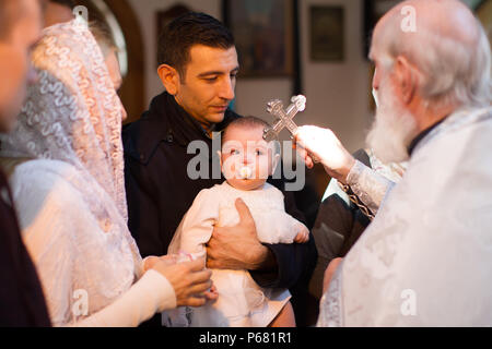 La Bielorussia, Gomel, 25 marzo. 2018. La Chiesa Prudhkovsky.Il battesimo di un bambino.Durante il battesimo di un bambino, un uomo si kiss la croce Foto Stock