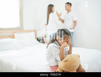 Asian bambina triste e piangeva mentre litigi genitore in camera da letto, foto design per problemi familiari e infelice nozione Foto Stock