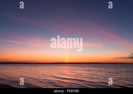 Un pilastro sole al tramonto visto da Seasalter vicino a Whitstable sulla costa della contea del Kent settentrionale. Foto Stock