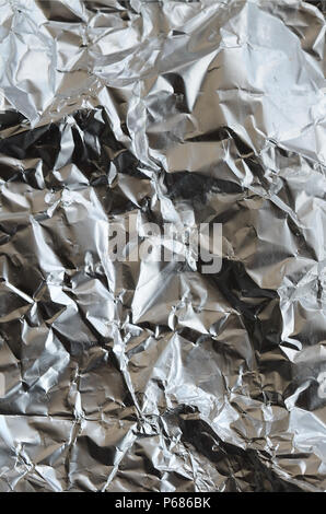 Sottile foglio stropicciato di frantumato di stagno argento alluminio foil sfondo con lucida superficie accartocciata per texture . Foto Stock