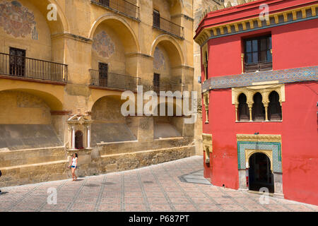 Una giovane spagnola cammina da sola passando davanti alle mura moresche porticate della Cattedrale-Moschea (la Mezquita) nella Plaza del Triunfo, Cordoba, Andalusia. Foto Stock