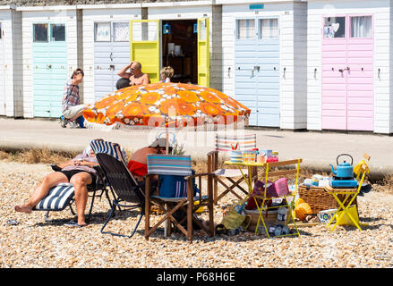 Lyme Regis, Dorset, Regno Unito. Il 29 giugno, 2018. Regno Unito: meteo locali e turisti affollano la spiaggia per godervi più caldo sole e cielo blu nella località balneare di Lyme Regis come registrare le temperature di rottura sono impostati per continuare in luglio. Un colorato ombrellone e tavolo da picnic al di fuori della spiaggia di capanne su Marine Parade. Credito: DWR/Alamy Live News Foto Stock