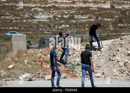 Ramallah, West Bank, Territorio palestinese. Il 29 giugno, 2018. I dimostranti palestinesi scagliare sassi verso le truppe israeliane durante scontri a seguito di una dimostrazione vicino l'insediamento ebraico di Beit El, vicino a Ramallah in Cisgiordania occupata Giugno 29, 2018 Credit: Shadi Hatem APA/images/ZUMA filo/Alamy Live News Foto Stock