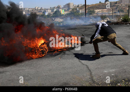 Ramallah, West Bank, Territorio palestinese. Il 29 giugno, 2018. Un manifestante palestinese brucia pneumatici durante gli scontri con le truppe israeliane a seguito di una dimostrazione vicino l'insediamento ebraico di Beit El, vicino a Ramallah in Cisgiordania occupata Giugno 29, 2018 Credit: Shadi Hatem APA/images/ZUMA filo/Alamy Live News Foto Stock