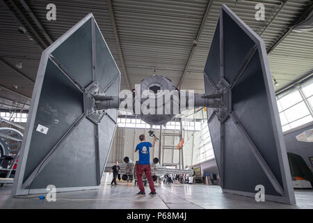 Stuttgart, Germania. Il 29 giugno, 2018. Un giornalista sta sotto una replica del 'Tie-Fighter' da Star Wars durante la fase di preparazione della cultura pop fair 'Comic Con la Germania". Il Fumetto con la Germania avrà luogo dal 20 giugno al 01 luglio. Credito: Marijan Murat/dpa/Alamy Live News Foto Stock