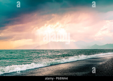 Bella estate seascape con montagne silhouette. Nuvoloso cielo rosa con sunray attraverso le nuvole. Spiaggia di Salerno, Italia Foto Stock