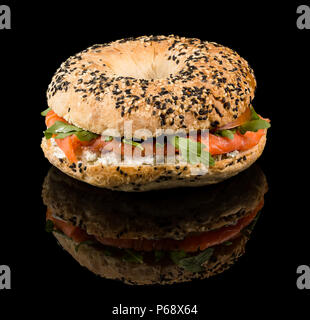 Bagel Salmone affumicato - sfornato fresco bagel, crema di formaggio e rabboccato con salmone affumicato e cipolle rosse con la riflessione isolata su sfondo nero Foto Stock