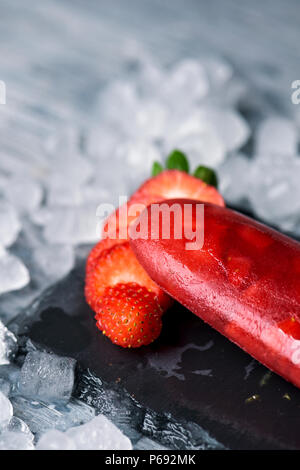 Closseup di ghiaccio in casa pop fatta con fragole naturale, su un naturale vassoio ardesia circondato da ghiaccio Foto Stock