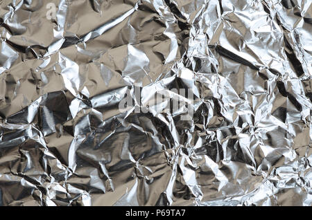 Sottile foglio stropicciato di frantumato di stagno argento alluminio foil sfondo con lucida superficie accartocciata per texture . Foto Stock