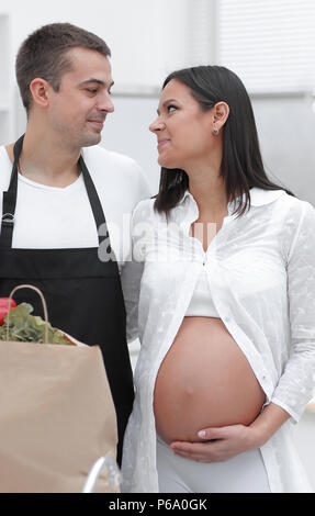 Il marito e la moglie incinta pettinatura sono attraverso il pack,in piedi in cucina Foto Stock