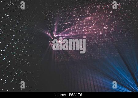 I raggi di luce attraverso piccoli fori in un buio spazio di metallo Foto Stock