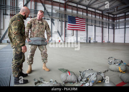 Stati Uniti Esercito il Mag. Cristopher D. Murphy, 982nd combattere la società della fotocamera (airborne), East Point, Ga.,commander, aiuta un paracadutista tedesco a prepararsi per un US/Deutschland amicizia Jump, Ramstein Air Force Base, 25 maggio 2016. Lo scopo dell'amicizia jump è di promuovere e alimentare degli Stati Uniti e le relazioni tedesche, sviluppare l'interoperabilità durante il corso di formazione e di fornire una base per le future operazioni in formazione e in ambienti reali. (U.S. Esercito foto di Spc. Tracy McKithern/rilasciato) Foto Stock