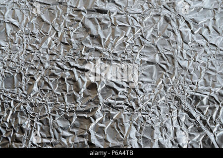 Sottile foglio stropicciato di frantumato di stagno argento alluminio foil sfondo con lucida superficie accartocciata per texture . Foto Stock