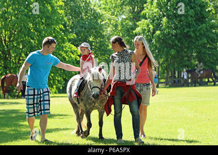 Una famiglia lettone gode di un pony ride durante il giorno di Gauja celebrazione, 28 maggio nel Adazi, Lettonia. I soldati assegnati a F Troop, 2° squadriglia e B Batteria, campo squadrone di artiglieria, 2° reggimento di cavalleria nelle regioni di funzionamento di supporto Atlantic risolvere ha partecipato alla annuale celebrazione estiva ospitando una visualizzazione statica con vari veicoli e armi. (U.S. Esercito foto di Sgt. Paige Behringer, decimo premere Camp la sede centrale) Foto Stock