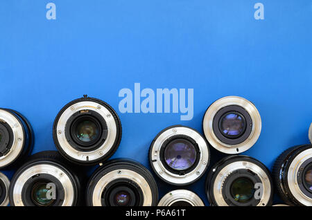 Diversi obiettivi fotografici giacciono su un brillante sfondo blu. Spazio per il testo . Foto Stock