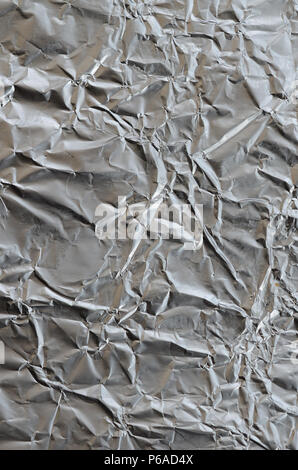Sottile foglio stropicciato di frantumato di stagno argento alluminio foil sfondo con lucida superficie accartocciata per texture . Foto Stock