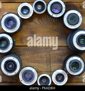 Diversi obiettivi fotografici giacciono su di un legno marrone dello sfondo. Spazio per il testo . Foto Stock