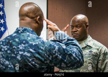 Master Sgt. Antone Scott, 96A Gruppo di manutenzione, saluta il suo fratello gemello, Lt. La Cmdr. Anthony Scott, dopo aver recitato il giuramento di arruolamento 31 Maggio a Eglin Air Force Base, Fla. questa è la seconda volta che i gemelli hanno partecipato ad un arruolamento cerimonia insieme. La prima volta è stato nel 2013. Questa integrazione consente Antone a mettere su il suo anziano comandante sergente stripe. (U.S. Air Force foto/Samuel King Jr.) Foto Stock