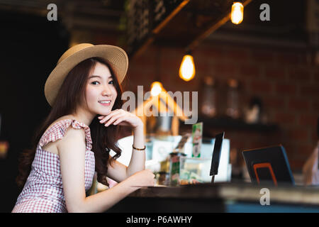 Ritratto di carino e bella asiatica ragazza sorridente in un coffee shop con copia spazio. Cafe cultura uno stile di vita informale, viaggiatore contento concetto donna Foto Stock