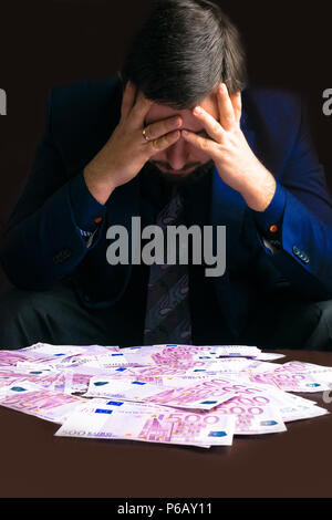 Reddito in contanti. Businesman seduto con il suo guadagnare denaro contante in euro dopo una dura giornata, la sua testa abbassata. Uomo in uomini vestiti. Un sacco di denaro euro. Corrompere e co Foto Stock