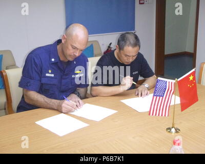 La Cmdr. Jon Kreischer (sinistra), comandante della USCGC Alex Haley (WMEC 39), segni sulla custodia del peschereccio gestito da al comandante della Repubblica popolare di Cina Coast Guard nave pattuglia 2301 nelle acque internazionali del Mare del Giappone, 21 giugno 2018. L'Alex Haley e PRC Coast Guard equipaggi scoperto un illecito di reti vietate dalla Convenzione internazionale durante una comune di imbarco sulla nave. Stati Uniti La guardia costiera della foto. Foto Stock