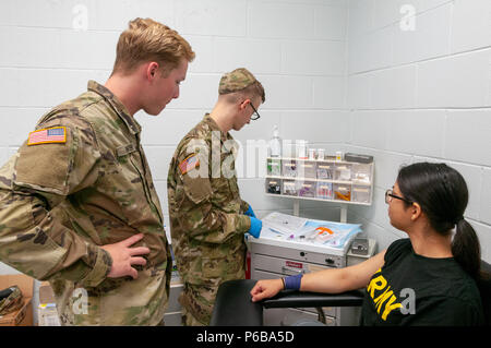 La Georgia Esercito Nazionale Guardsman PFC. Charles Baker del 3° Battaglione, 121 reggimento di fanteria che fornisce una guida per il suo compagno soldato Spc. Stephen Scott come egli ottiene pronto a prelevare il sangue dal PFC. Gabriela Ruiz della 138th Chemical company durante il mese di giugno 24, 2018 soldato elaborazione di fattibilità presso il Camp di argilla, Marietta in Georgia. Foto Stock