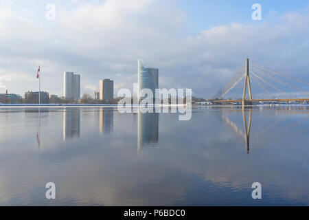 La Riga terrapieno vicino al fiume Daugava in un inverno gelido Giornata contro lo sfondo di un grattacielo e un cavo-alloggiato in parallelo con la riflessione Foto Stock