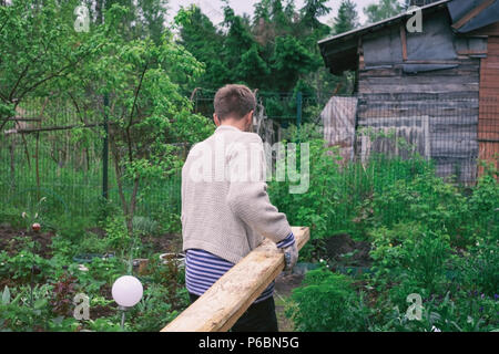 L'uomo portare il legname per la nuova casa. Vista posteriore Foto Stock