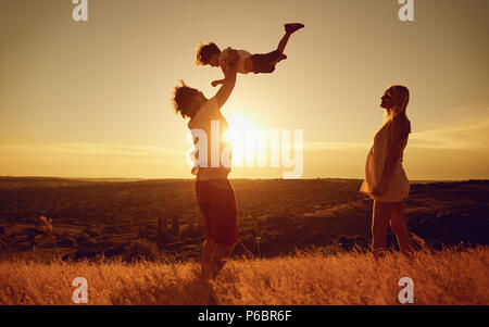 La famiglia felice divertirsi giocando al tramonto sulla natura. Foto Stock
