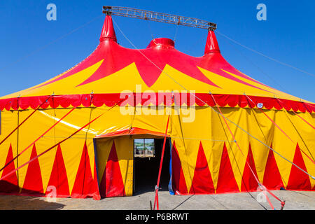 Tenda del circo o big top con rosso e giallo permanente di design fuori contro un cielo blu chiaro. Foto Stock