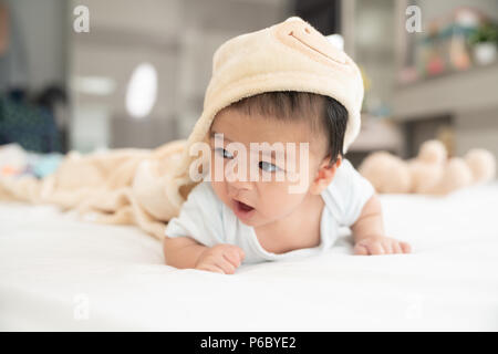 Ritratto di un bambino gattona sul letto in camera sua, adorabile baby boy in bianco e luminosa camera da letto, neonato relax nel letto, vivaio di giovani bambini Foto Stock