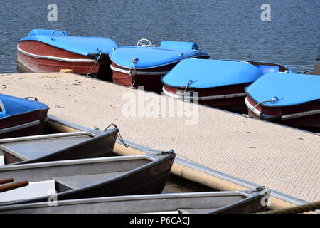 Vecchio e nostalgico pedalò e barche a remi su un molo, barca a remi e pedalò parcheggiato in una linea di dock di un lago in Baviera Foto Stock