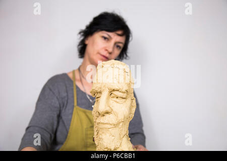 Artista scultore creando un busto scultura con argilla. È felice della sua opera, lei è concentrata, ella è scolpire una donna. Foto Stock