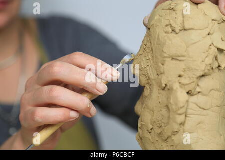 Artista scultore creando un busto scultura con argilla. È felice della sua opera, lei è concentrata, ella è scolpire una donna Foto Stock