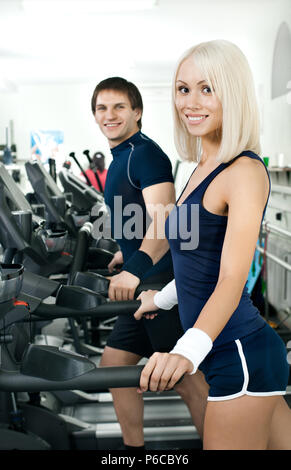 Felice ragazza atletico e guy, esecuzione di esercizio sulla via di corsa e sorriso, nello sport-hall Foto Stock