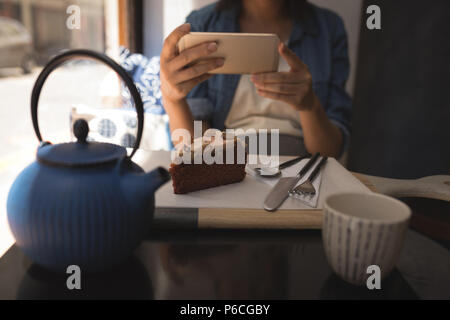Donna incinta prendendo foto di pasticceria con il telefono cellulare Foto Stock