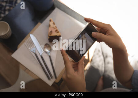 Donna incinta prendendo foto di pasticceria con il telefono cellulare Foto Stock