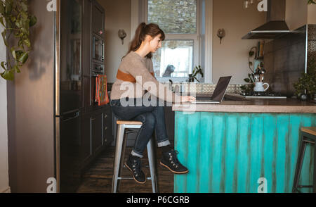 Donna con notebook in cucina Foto Stock