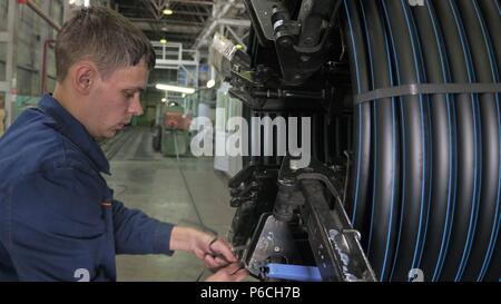 RUSSIA, ANGARSK - Giugno 8, 2018: bobina bobina di filettatura tubo. Fabbricazione di plastica tubazioni di acqua alla fabbrica. Processo per la fabbricazione di tubi in materiale plastico in ma Foto Stock