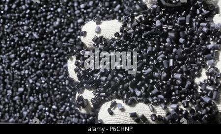 In plastica grigio nero granulato briciola. Fabbricazione di plastica tubazioni di acqua della fabbrica. Processo per la fabbricazione di tubi di plastica sulla macchina utensile con l'u Foto Stock