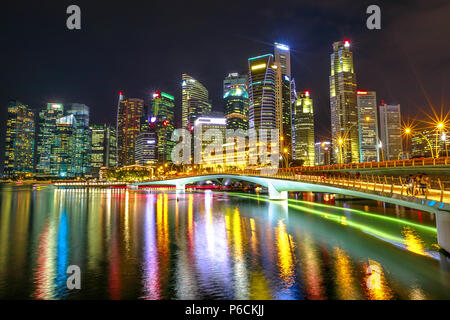 Singapore edifici finanziari e grattacieli del centro cittadino di riflesso nel mare del porto. Lo skyline di Singapore di notte. Scena notturna lungomare di Marina Bay. Foto Stock