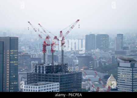 Gru edili sulla parte superiore della costruzione dell'edificio contro skyline della città Foto Stock