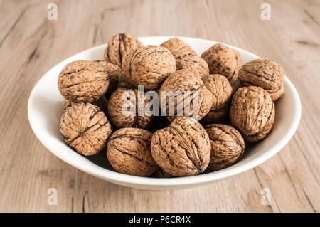 Un mucchio di intere orgranic noci comuni in guscio closeup nel vaso di porcellana Foto Stock