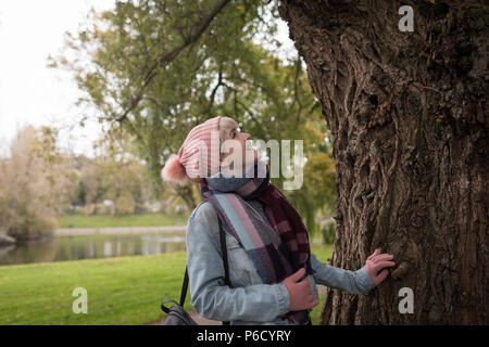 Donna in abiti invernali guardando tree Foto Stock