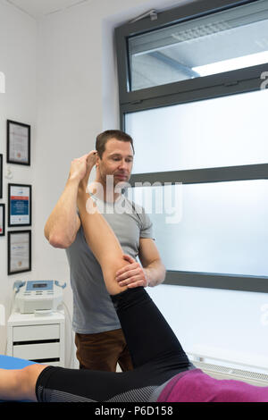 Fisioterapista dando massaggio delle gambe per donna Foto Stock