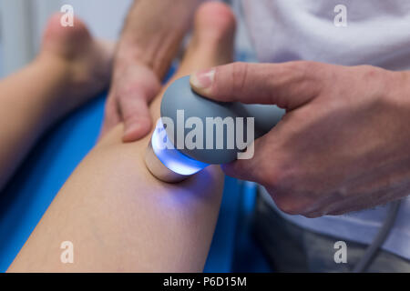 Fisioterapista dando massaggio delle gambe di donna con la macchina Foto Stock