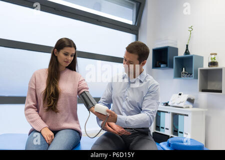 Fisioterapista controllando la pressione del sangue della donna Foto Stock