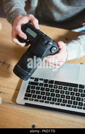 Uomo che utilizza una fotocamera digitale in casa Foto Stock